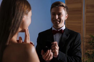 Photo of Smiling man with engagement ring making marriage proposal to his girlfriend at home