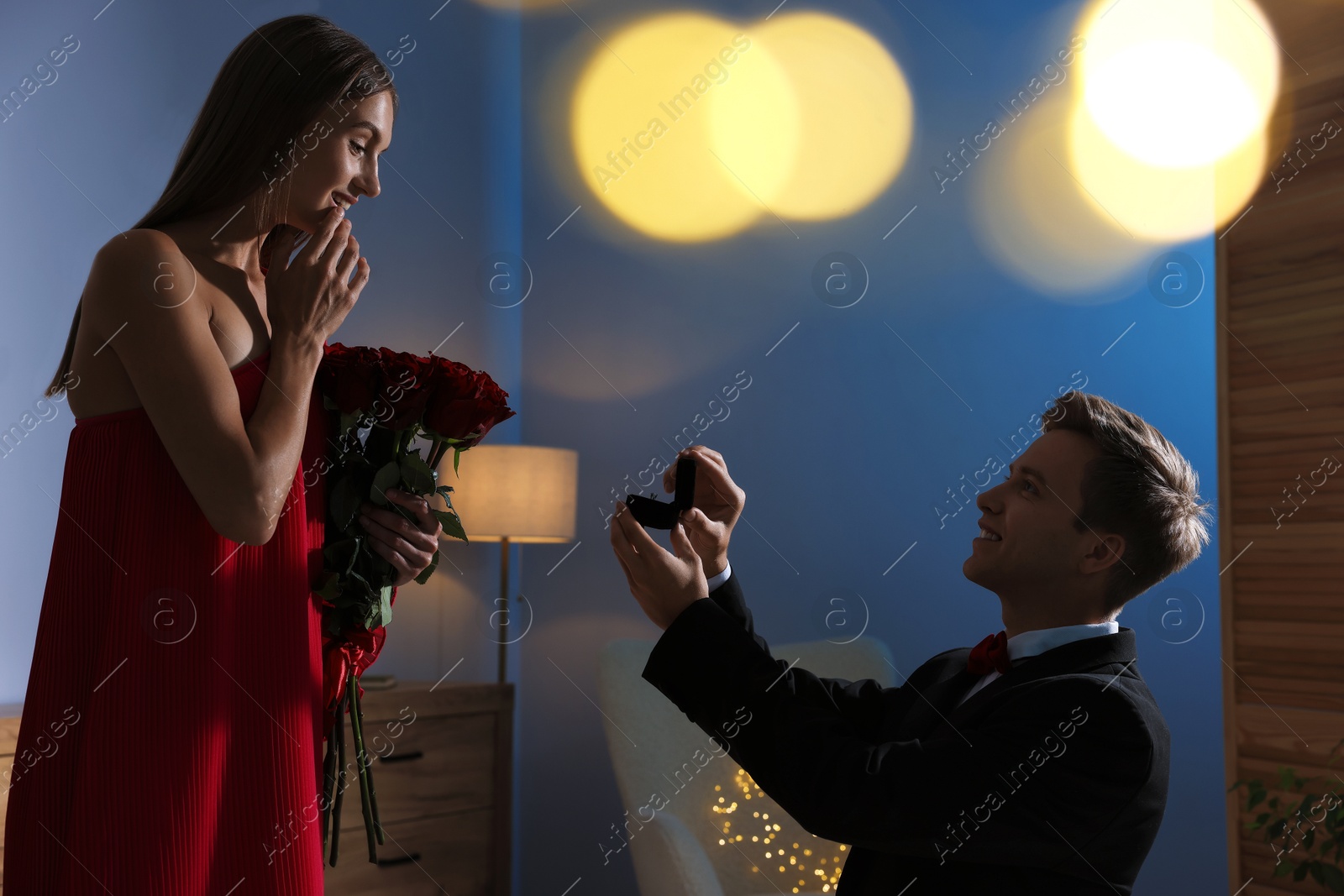 Smiling man with engagement ring making marriage proposal to his happy girlfriend in dark room. Bokeh effect Photo of Smiling man with engagement ring making marriage proposal to his happy girlfriend in dark room. Bokeh effect