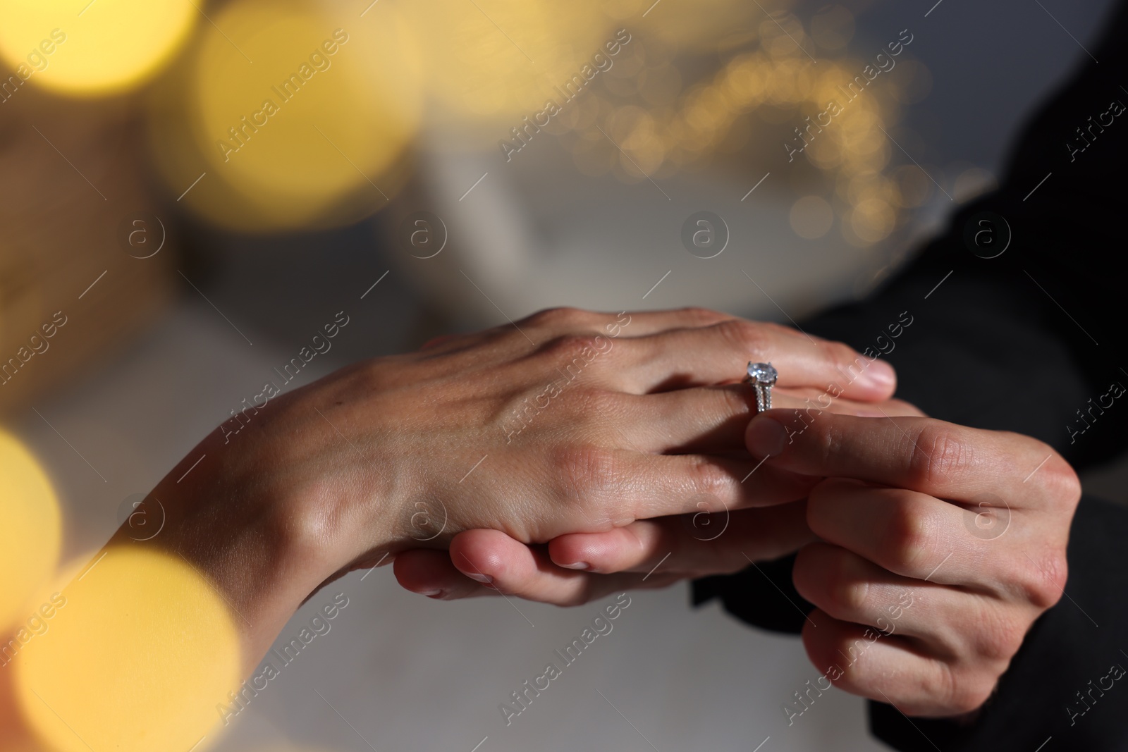 Making marriage proposal. Man putting engagement ring onto his girlfriend's finger at home, closeup. Bokeh effect Photo of Making marriage proposal. Man putting engagement ring onto his girlfriend's finger at home, closeup. Bokeh effect