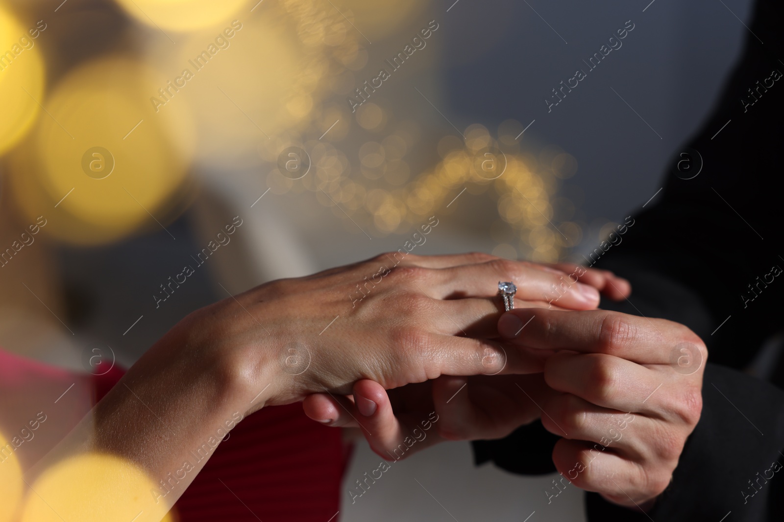 Making marriage proposal. Man putting engagement ring onto his girlfriend's finger at home, closeup. Bokeh effect Photo of Making marriage proposal. Man putting engagement ring onto his girlfriend's finger at home, closeup. Bokeh effect
