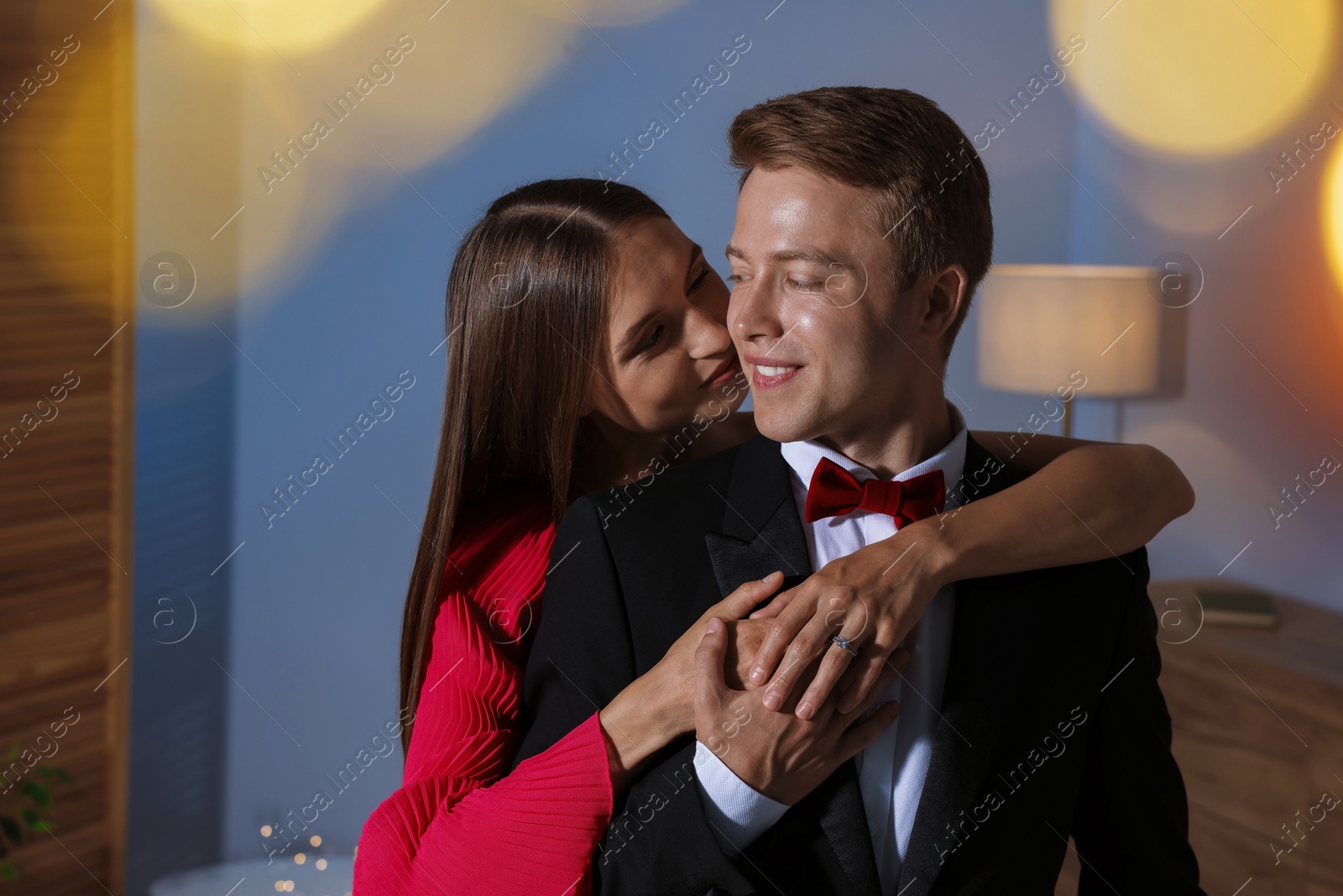 Making marriage proposal. Woman with engagement ring and her smiling fiance hugging at home. Bokeh effect Photo of Making marriage proposal. Woman with engagement ring and her smiling fiance hugging at home. Bokeh effect
