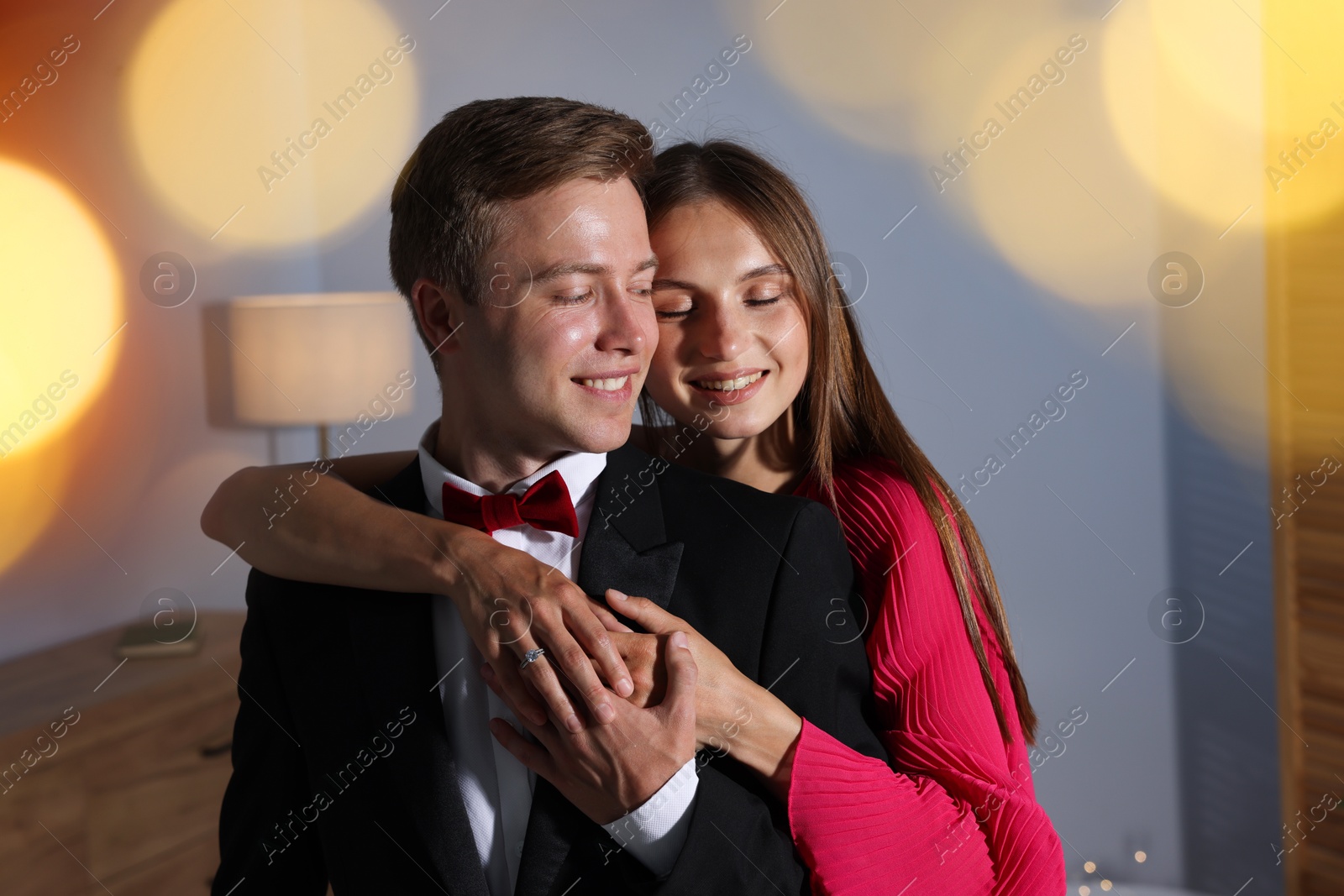 Making marriage proposal. Woman with engagement ring and her smiling fiance hugging at home. Bokeh effect Photo of Making marriage proposal. Woman with engagement ring and her smiling fiance hugging at home. Bokeh effect