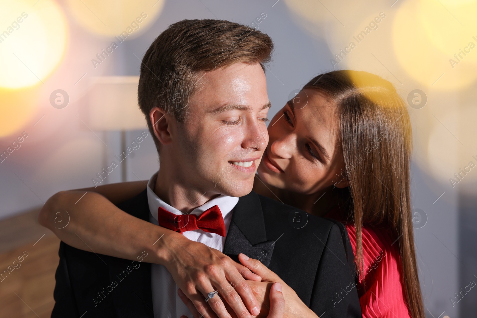 Making marriage proposal. Woman with engagement ring and her smiling fiance hugging at home. Bokeh effect Photo of Making marriage proposal. Woman with engagement ring and her smiling fiance hugging at home. Bokeh effect