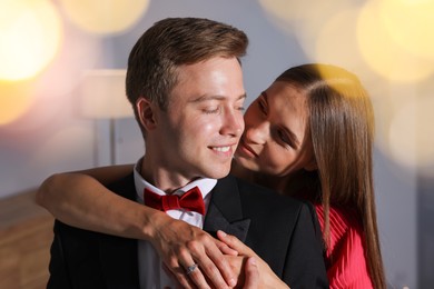 Photo of Making marriage proposal. Woman with engagement ring and her smiling fiance hugging at home. Bokeh effect