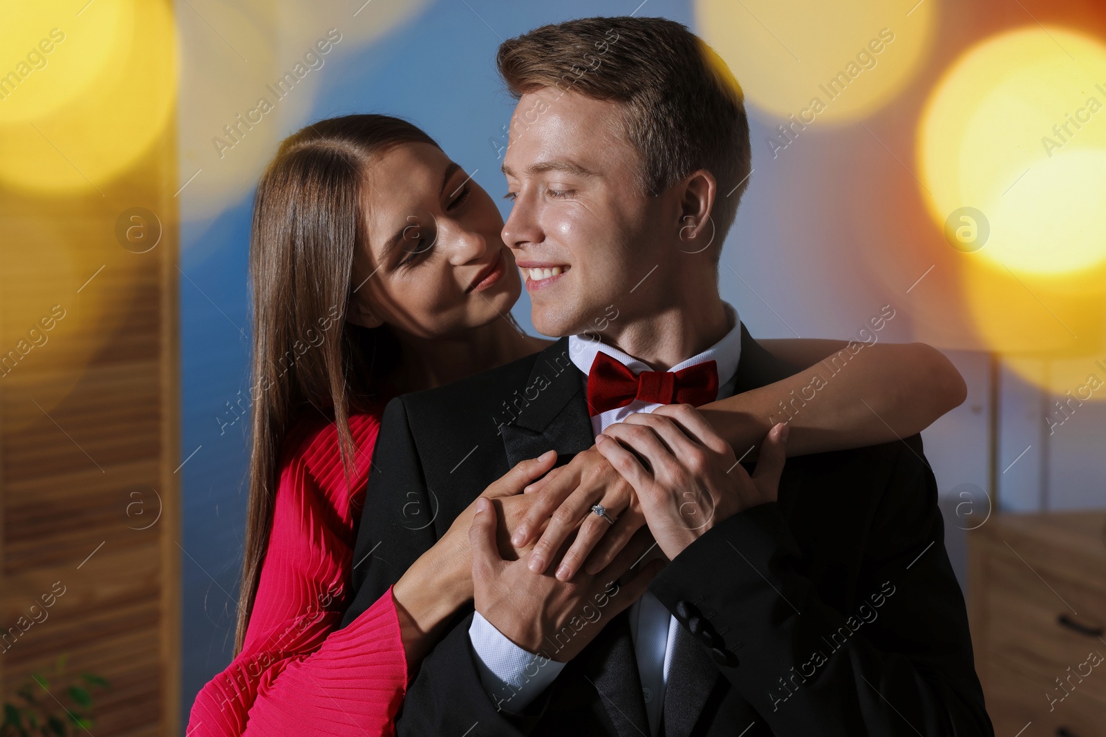 Making marriage proposal. Woman with engagement ring and her smiling fiance hugging at home. Bokeh effect Photo of Making marriage proposal. Woman with engagement ring and her smiling fiance hugging at home. Bokeh effect