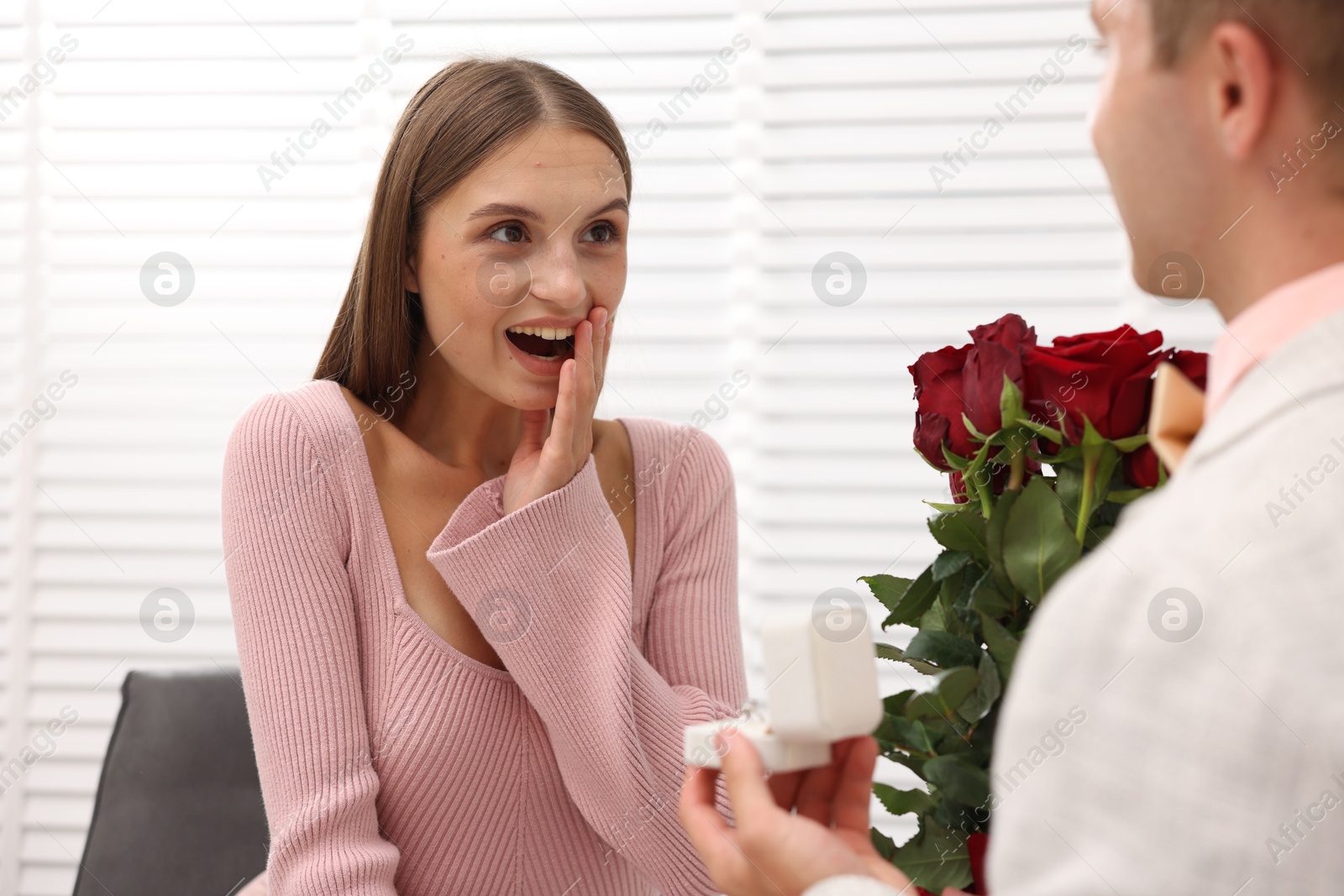 Man with engagement ring and bouquet of roses making marriage proposal to his emotional girlfriend at home, closeup Photo of Man with engagement ring and bouquet of roses making marriage proposal to his emotional girlfriend at home, closeup