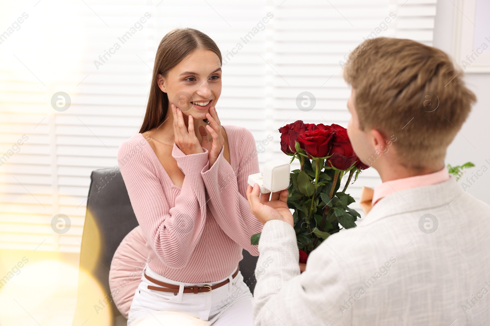 Man with engagement ring and bouquet of roses making marriage proposal to his happy girlfriend at home. Bokeh effect Photo of Man with engagement ring and bouquet of roses making marriage proposal to his happy girlfriend at home. Bokeh effect