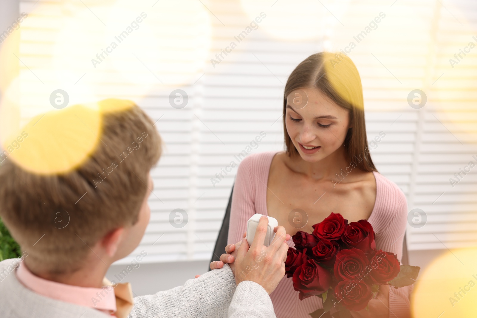 Man with engagement ring and bouquet of roses making marriage proposal to his happy girlfriend at home. Bokeh effect Photo of Man with engagement ring and bouquet of roses making marriage proposal to his happy girlfriend at home. Bokeh effect