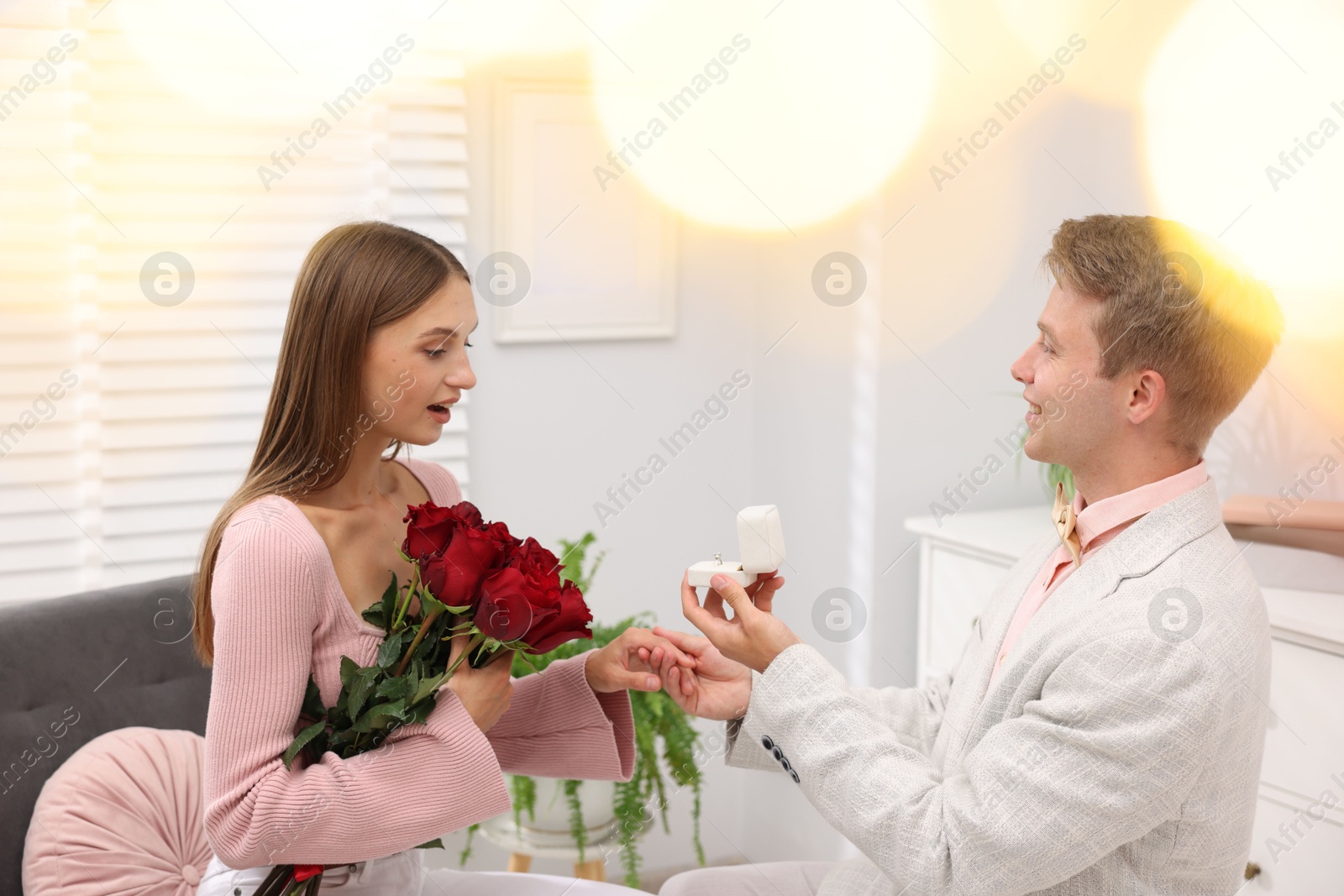 Man with engagement ring and bouquet of roses making marriage proposal to his happy girlfriend at home. Bokeh effect Photo of Man with engagement ring and bouquet of roses making marriage proposal to his happy girlfriend at home. Bokeh effect