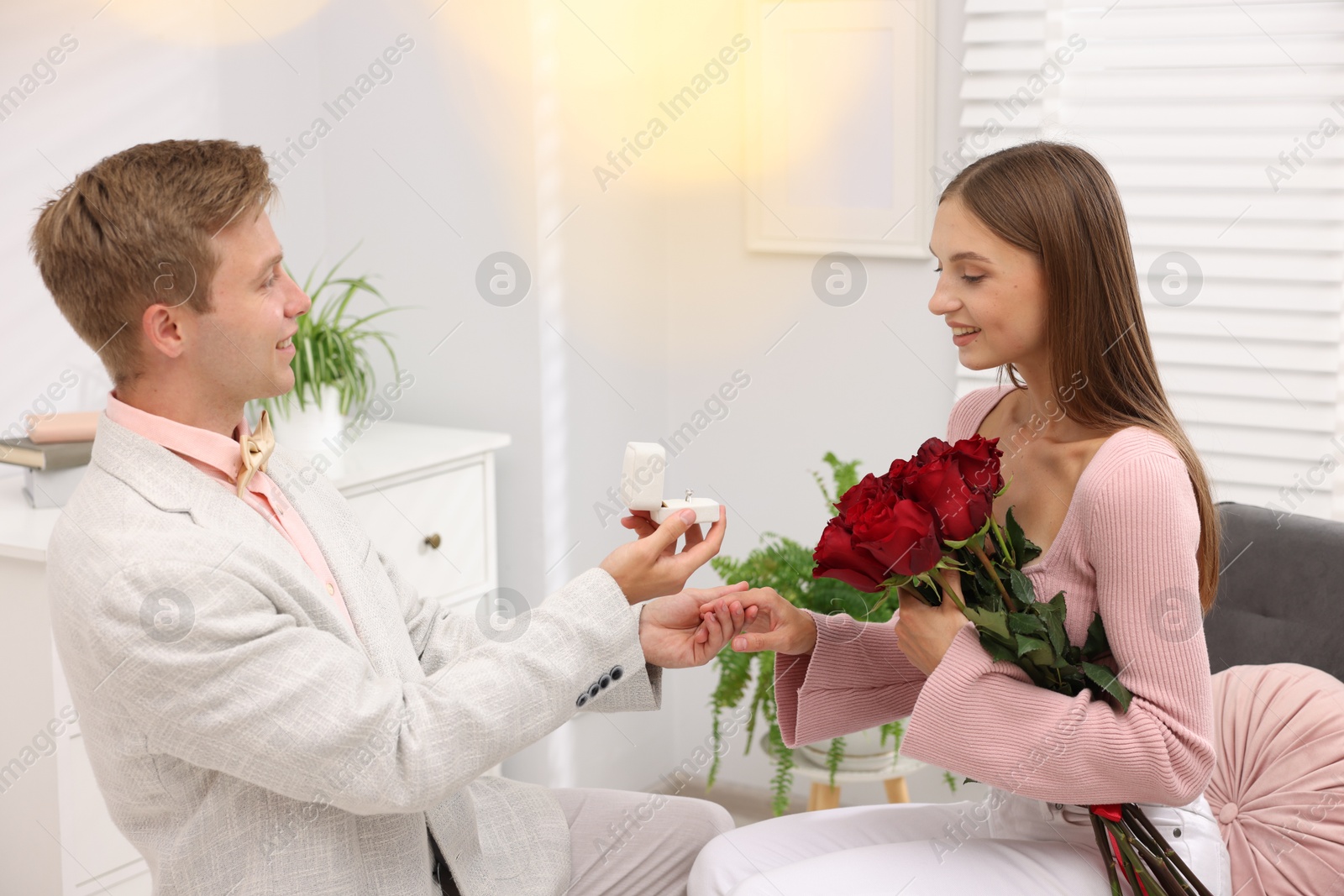 Man with engagement ring and bouquet of roses making marriage proposal to his happy girlfriend at home. Bokeh effect Photo of Man with engagement ring and bouquet of roses making marriage proposal to his happy girlfriend at home. Bokeh effect
