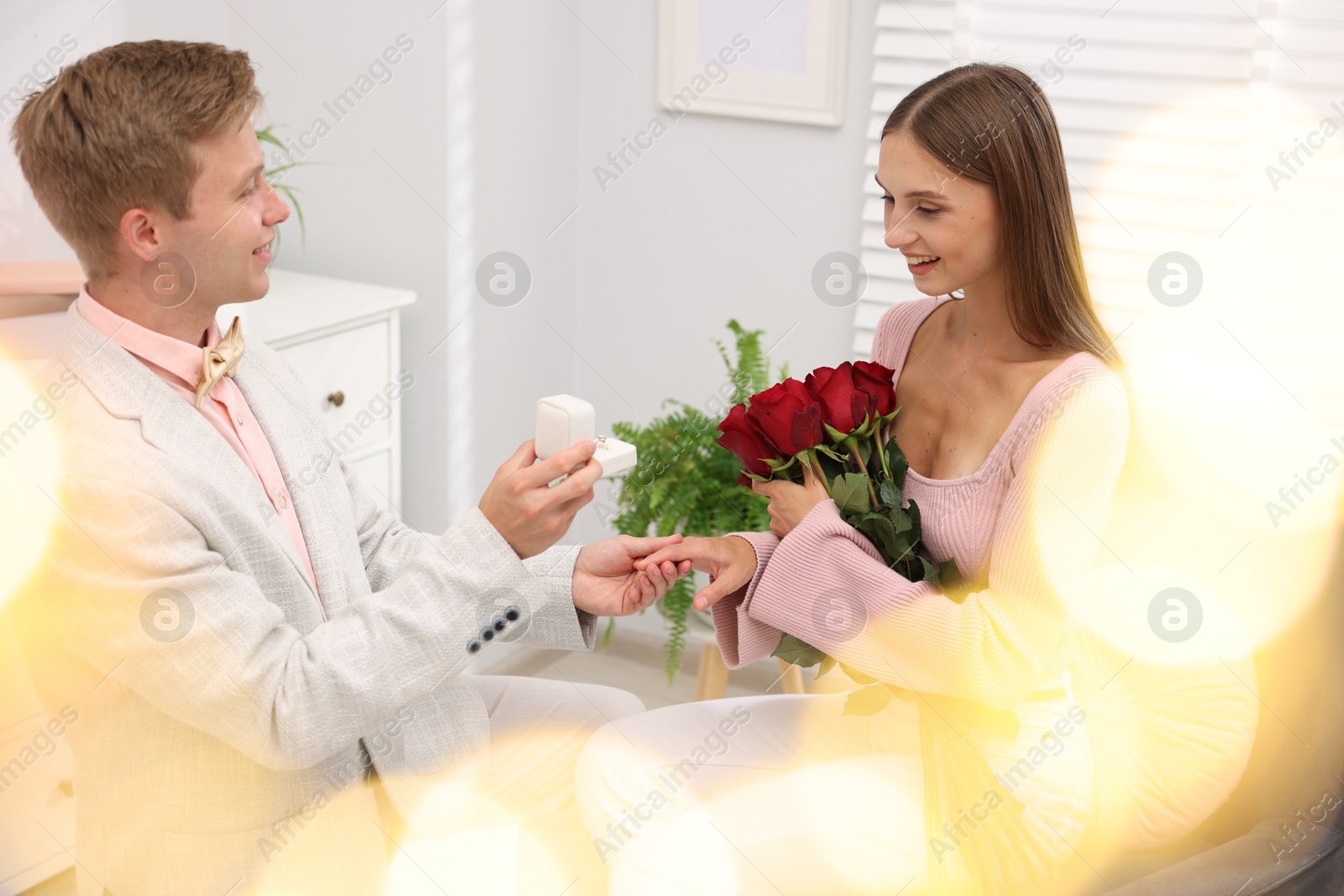 Man with engagement ring and bouquet of roses making marriage proposal to his happy girlfriend at home. Bokeh effect Photo of Man with engagement ring and bouquet of roses making marriage proposal to his happy girlfriend at home. Bokeh effect