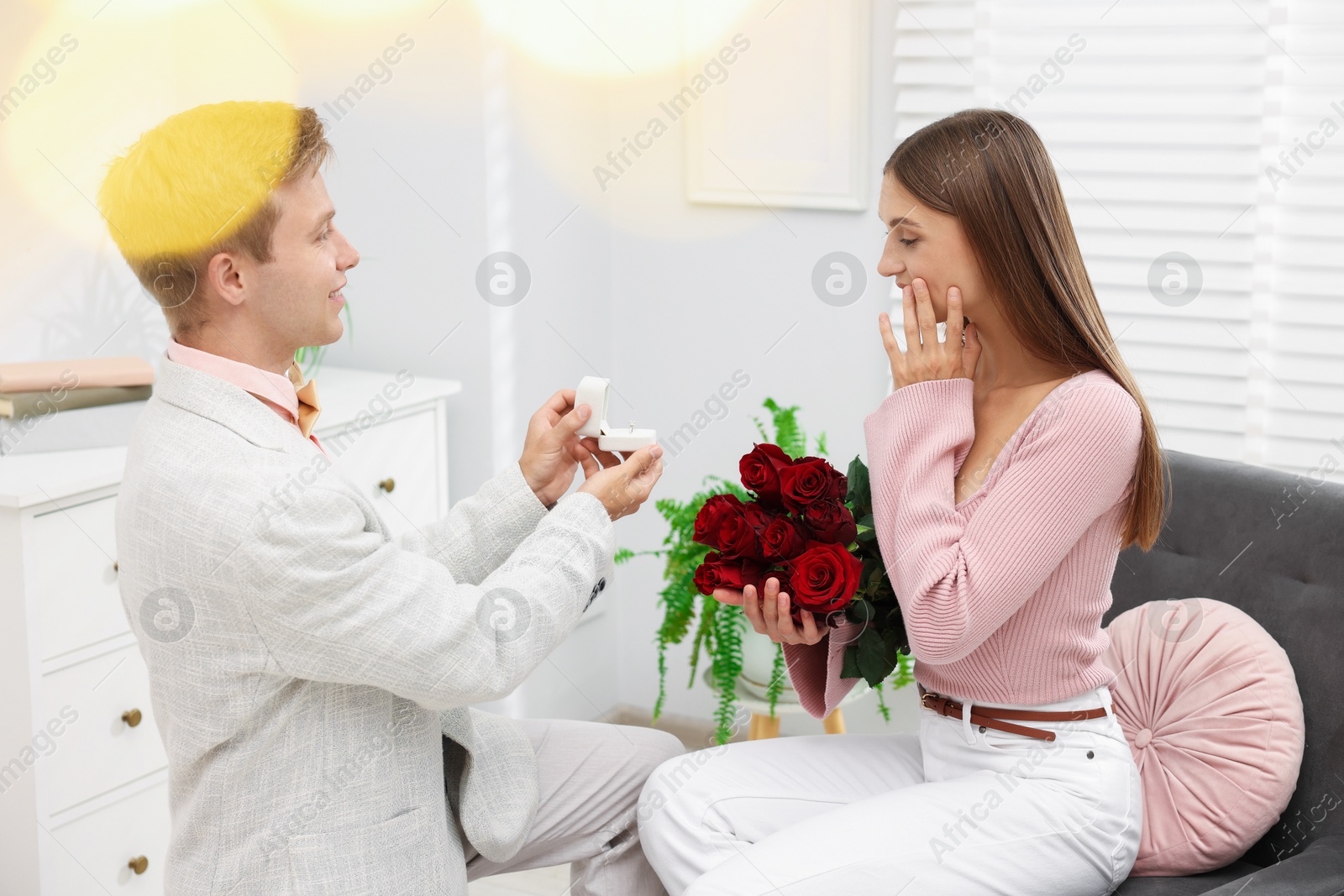Man with engagement ring and bouquet of roses making marriage proposal to his emotional girlfriend at home. Bokeh effect Photo of Man with engagement ring and bouquet of roses making marriage proposal to his emotional girlfriend at home. Bokeh effect