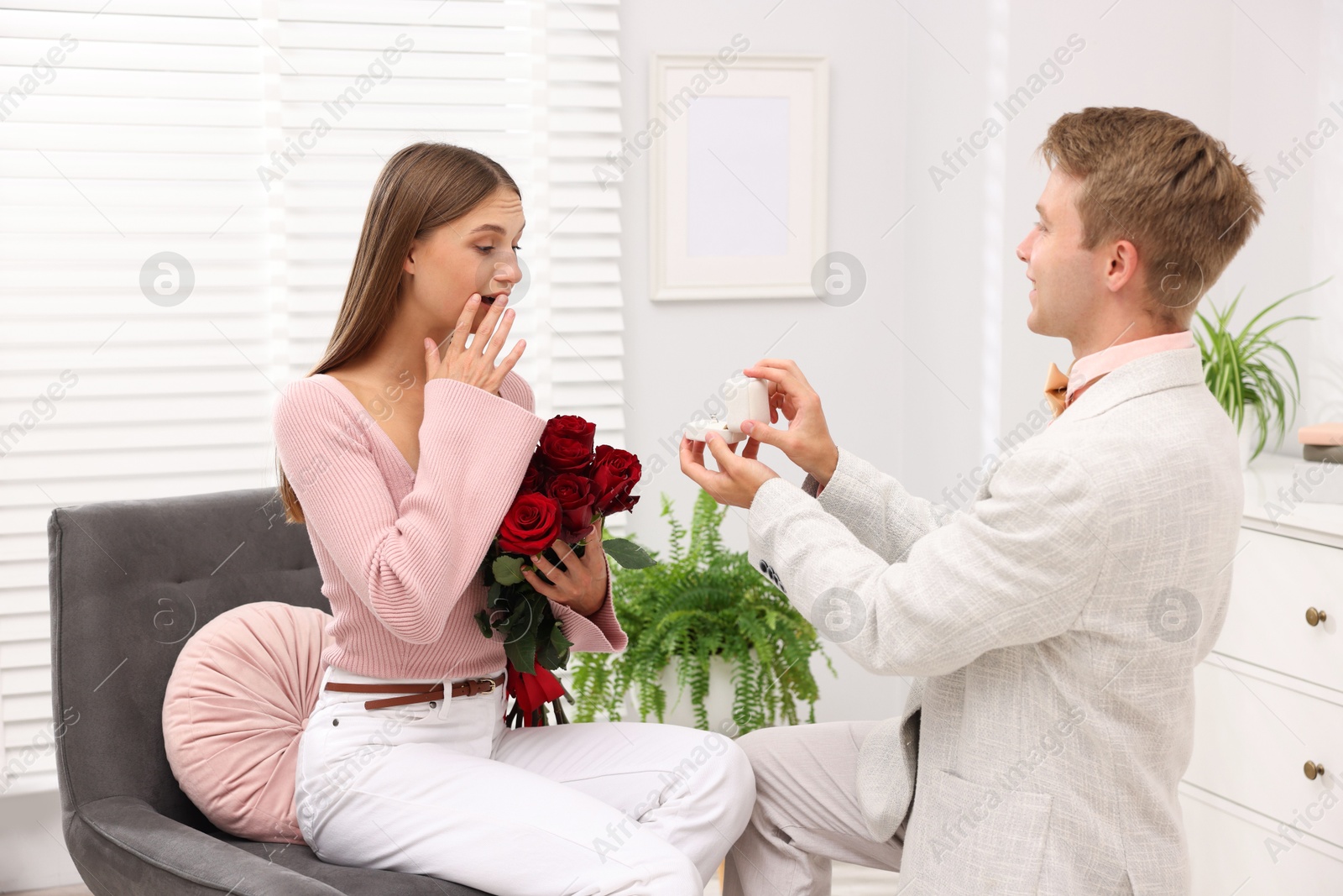Man with engagement ring and bouquet of roses making marriage proposal to his happy girlfriend at home Photo of Man with engagement ring and bouquet of roses making marriage proposal to his happy girlfriend at home