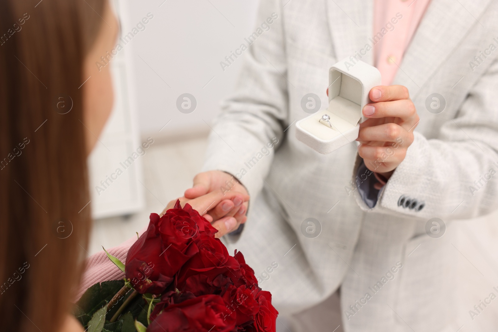 Man with engagement ring making marriage proposal to his girlfriend with bouquet of roses at home, closeup Photo of Man with engagement ring making marriage proposal to his girlfriend with bouquet of roses at home, closeup