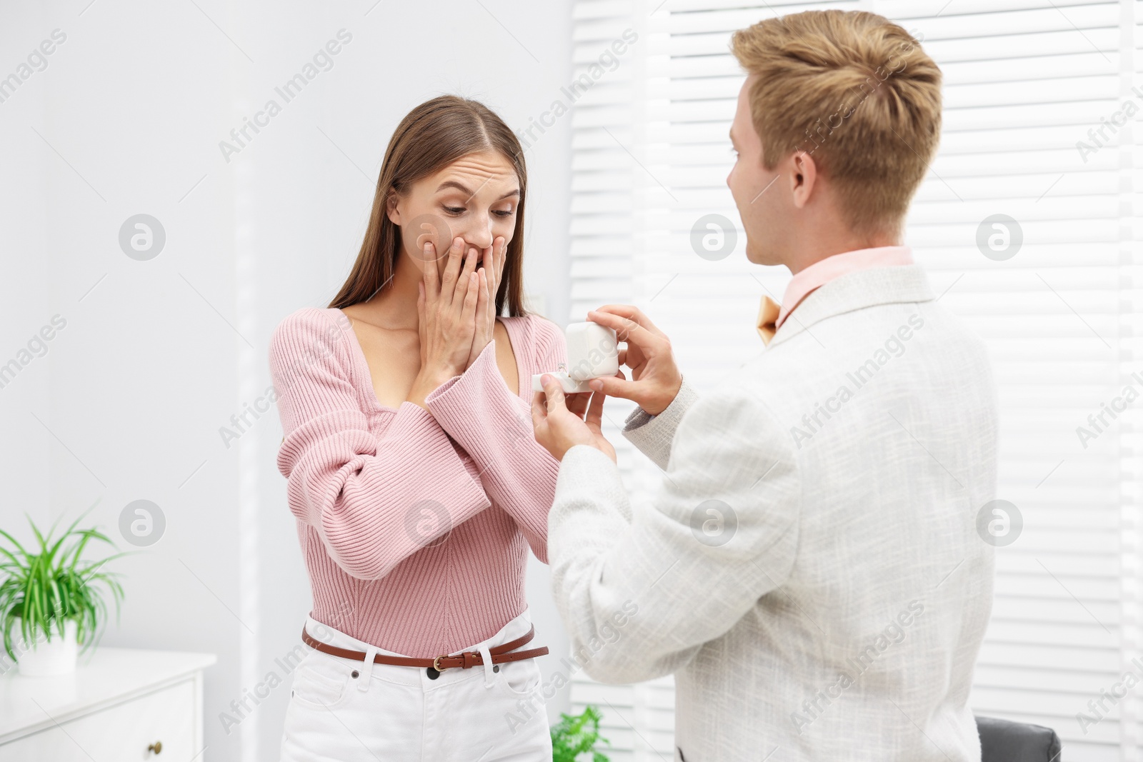 Man with engagement ring making marriage proposal to his surprised girlfriend at home Photo of Man with engagement ring making marriage proposal to his surprised girlfriend at home