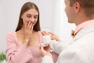 Photo of Man with engagement ring making marriage proposal to his happy girlfriend at home, closeup