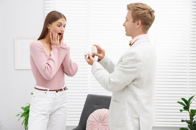 Photo of Man with engagement ring making marriage proposal to his surprised girlfriend at home