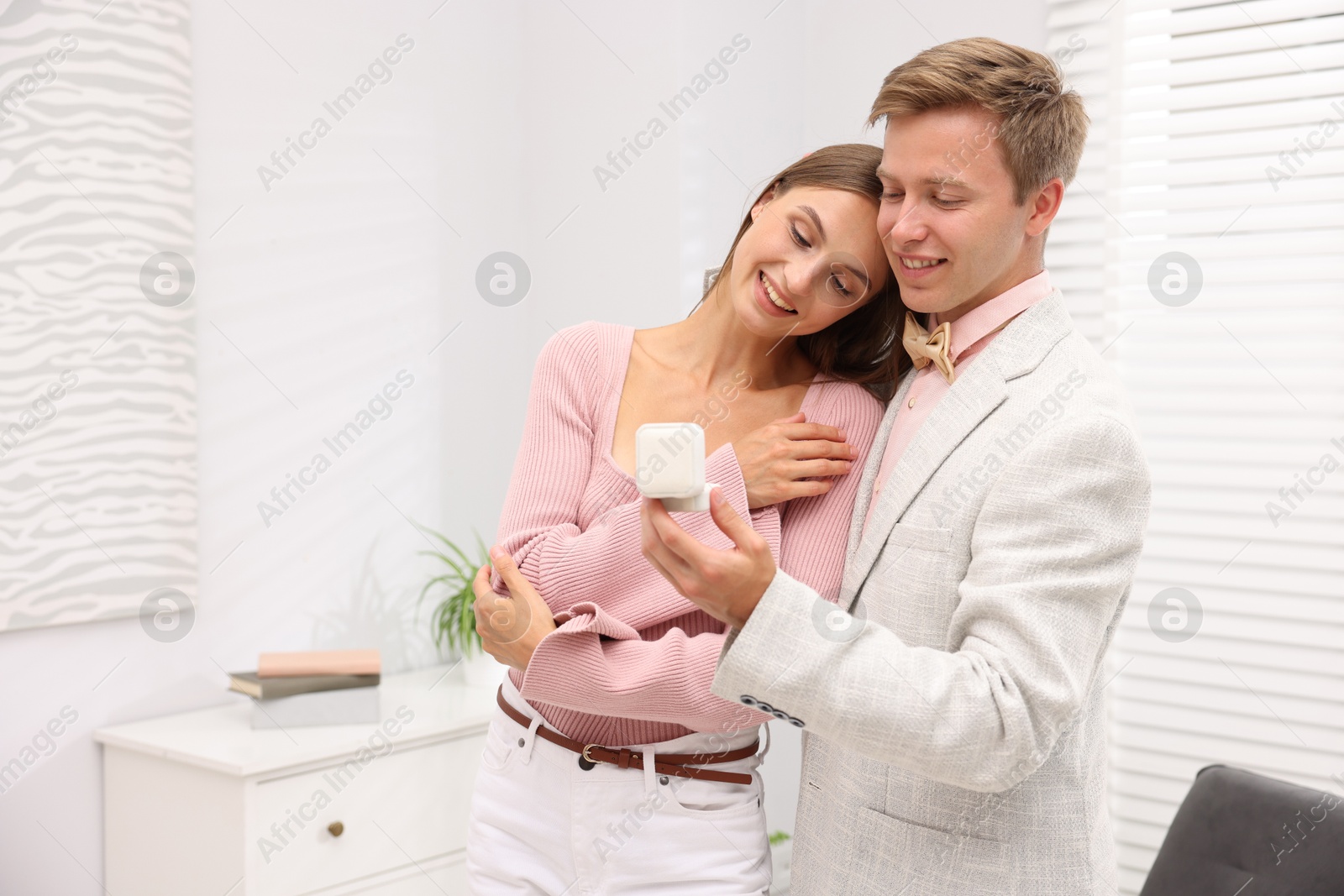 Marriage proposal. Smiling man with engagement ring and his happy girlfriend hugging at home, space for text Photo of Marriage proposal. Smiling man with engagement ring and his happy girlfriend hugging at home, space for text