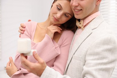 Photo of Marriage proposal. Smiling man with engagement ring and his girlfriend at home, closeup