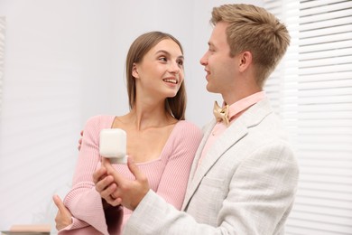 Photo of Marriage proposal. Smiling man with engagement ring and his happy girlfriend at home