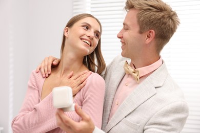 Photo of Marriage proposal. Smiling man with engagement ring and his happy girlfriend at home