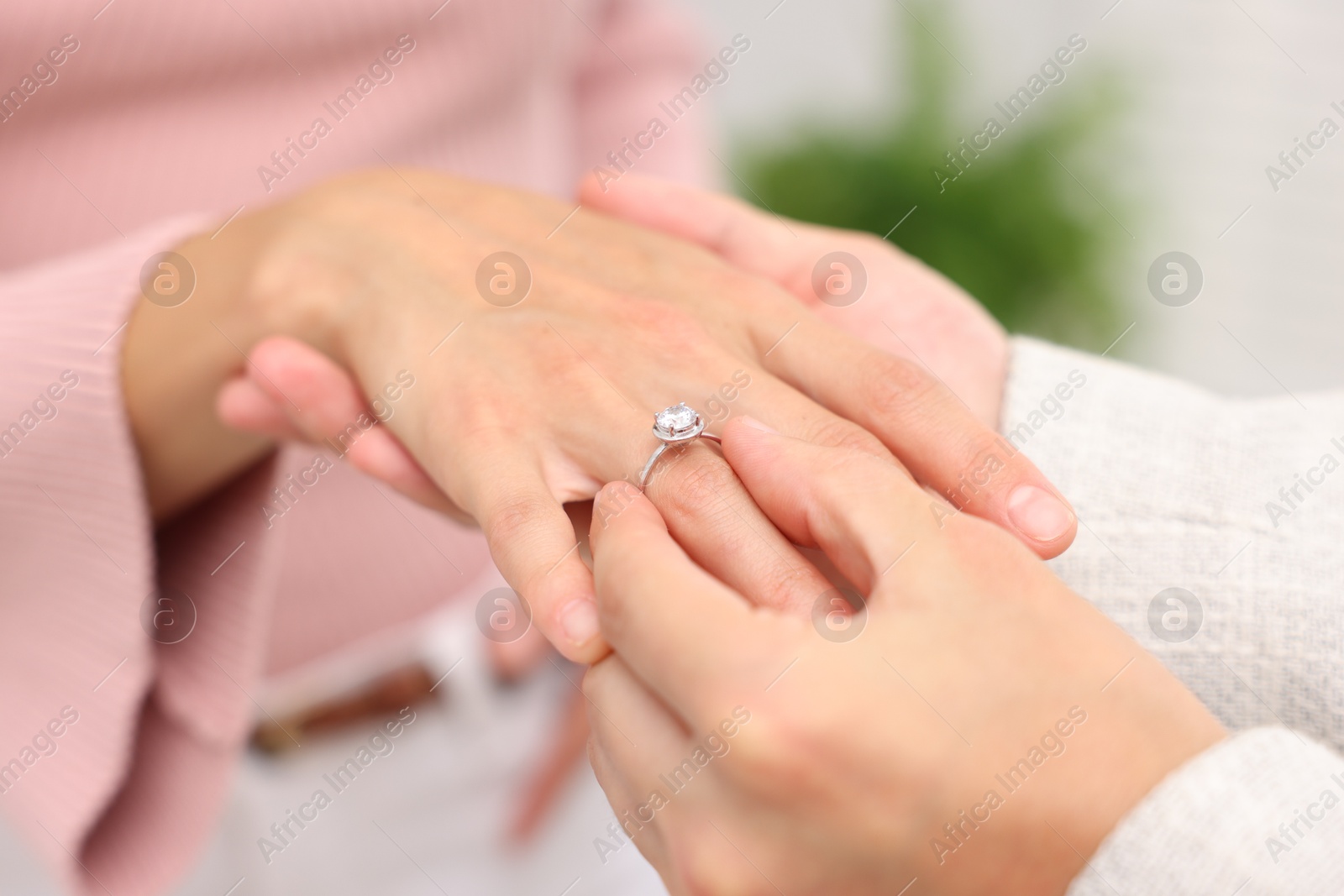 Making marriage proposal. Man putting engagement ring onto his girlfriend's finger at home, closeup Photo of Making marriage proposal. Man putting engagement ring onto his girlfriend's finger at home, closeup