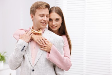 Photo of Making marriage proposal. Woman with engagement ring and her smiling fiance hugging in light room. Space for text