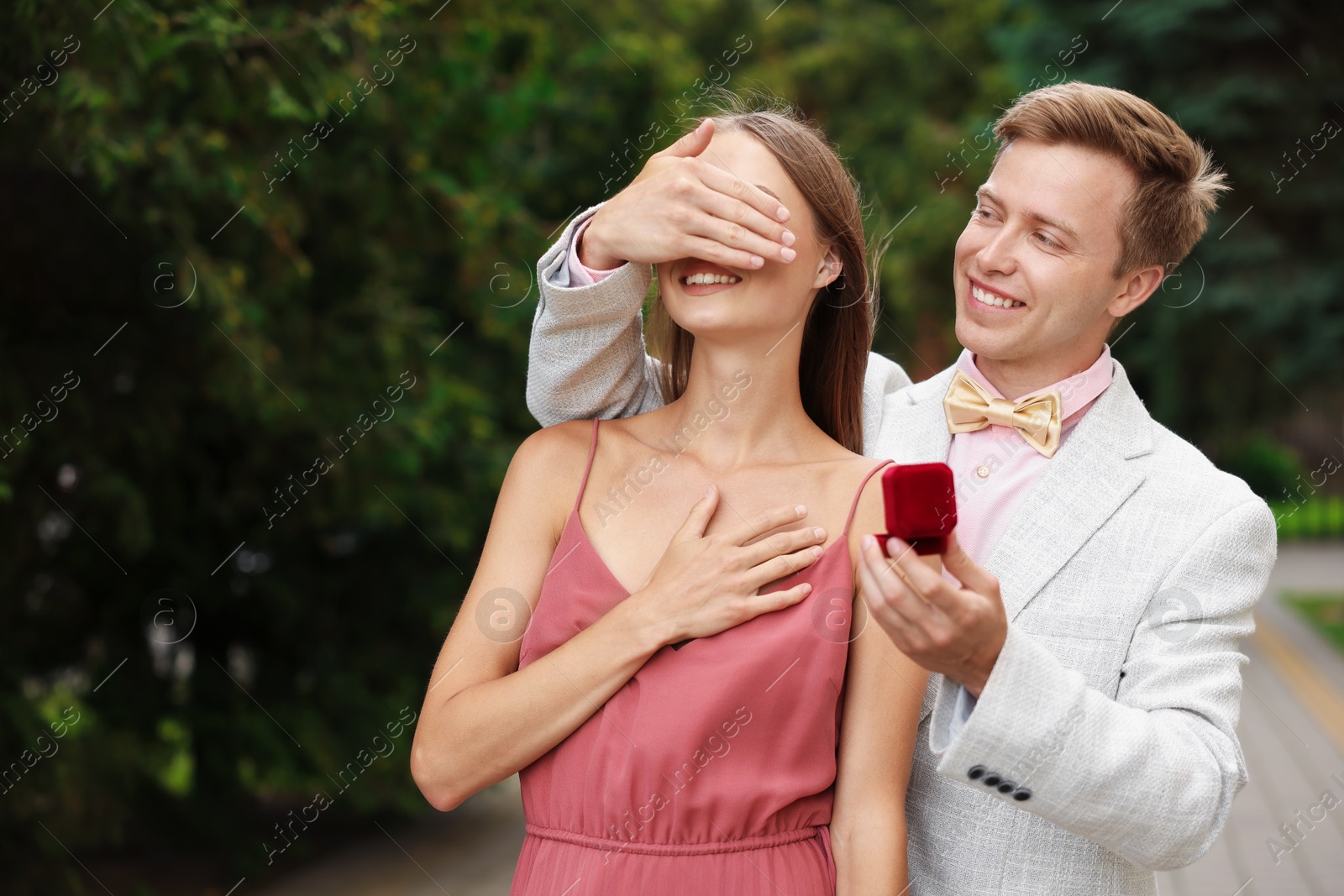Making marriage proposal. Smiling man with engagement ring surprising his girlfriend outdoors, space for text Photo of Making marriage proposal. Smiling man with engagement ring surprising his girlfriend outdoors, space for text