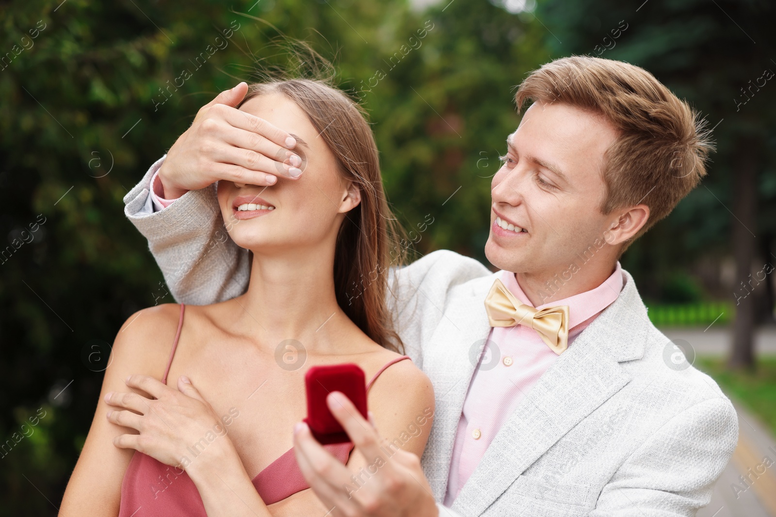 Making marriage proposal. Smiling man with engagement ring surprising his girlfriend outdoors Photo of Making marriage proposal. Smiling man with engagement ring surprising his girlfriend outdoors