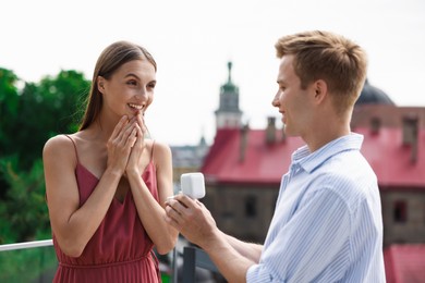 Photo of Man with engagement ring making marriage proposal to his happy girlfriend outdoors