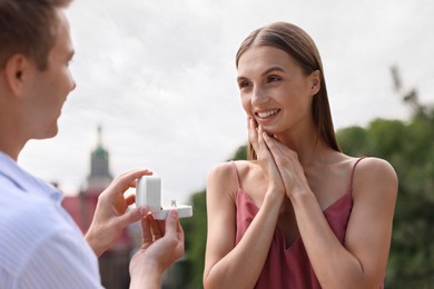 Photo of Man with engagement ring making marriage proposal to his happy girlfriend outdoors