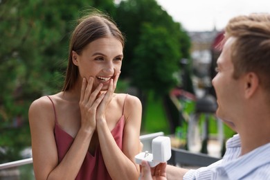 Photo of Man with engagement ring making marriage proposal to his happy girlfriend outdoors