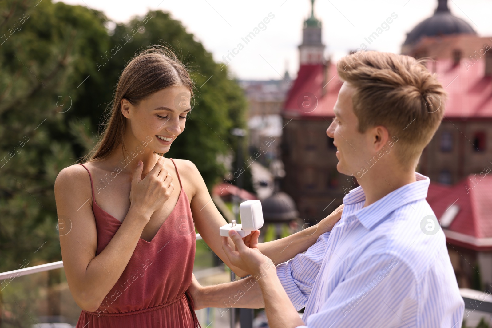 Man with engagement ring making marriage proposal to his happy girlfriend on balcony outdoors Photo of Man with engagement ring making marriage proposal to his happy girlfriend on balcony outdoors
