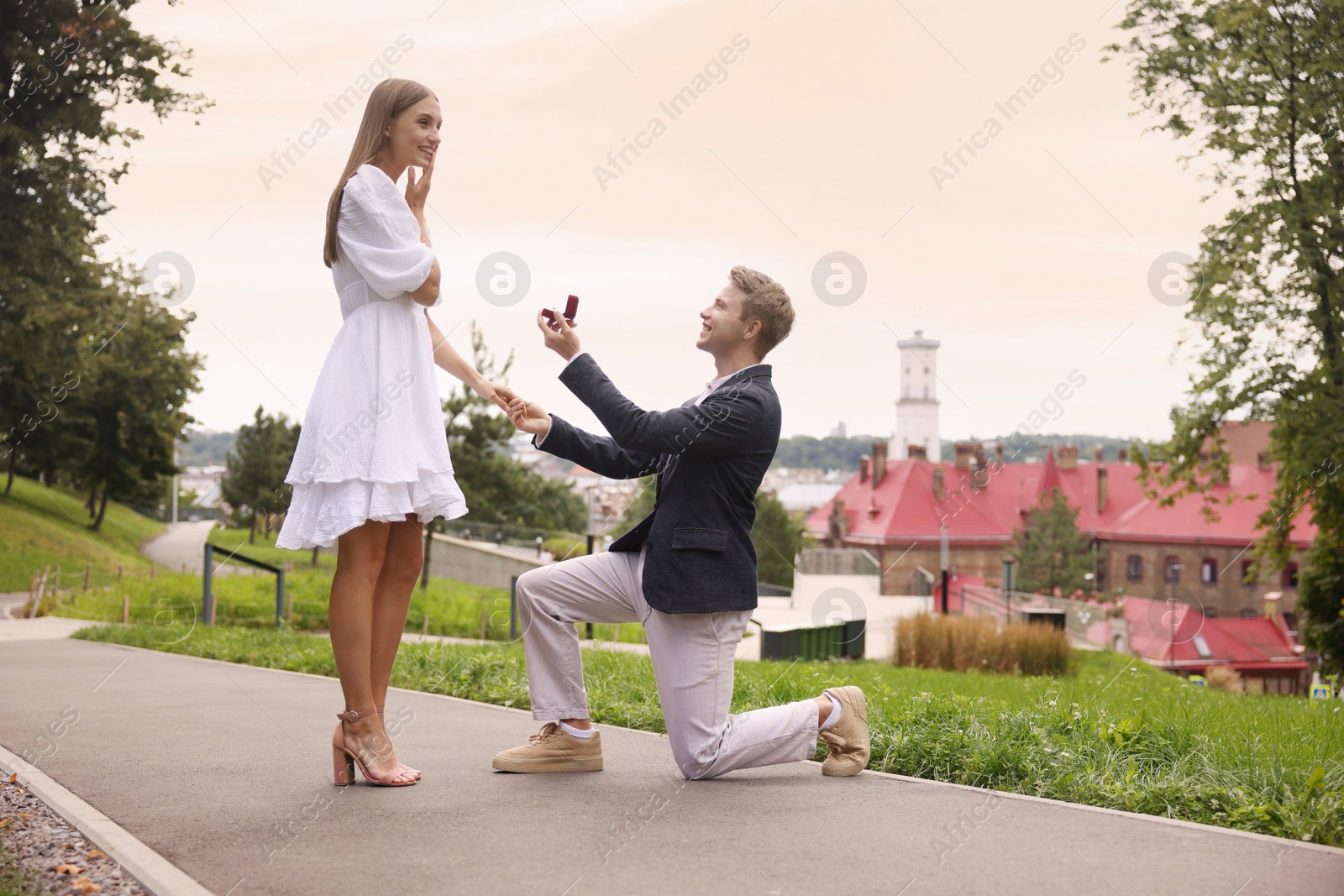 Man with engagement ring making marriage proposal to his happy girlfriend outdoors, low angle view Photo of Man with engagement ring making marriage proposal to his happy girlfriend outdoors, low angle view