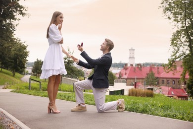 Photo of Man with engagement ring making marriage proposal to his happy girlfriend outdoors, low angle view