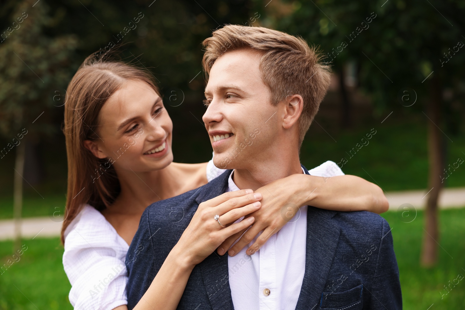 Marriage proposal. Woman with engagement ring hugging her smiling fiance outdoors Photo of Marriage proposal. Woman with engagement ring hugging her smiling fiance outdoors