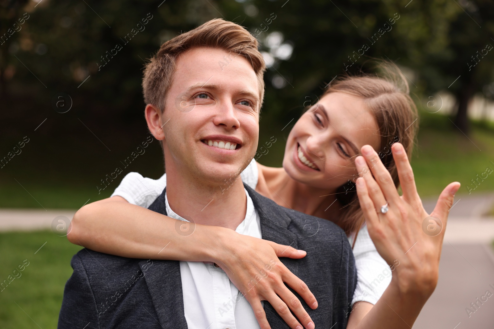 Marriage proposal. Smiling woman showing engagement ring and hugging her fiance outdoors Photo of Marriage proposal. Smiling woman showing engagement ring and hugging her fiance outdoors