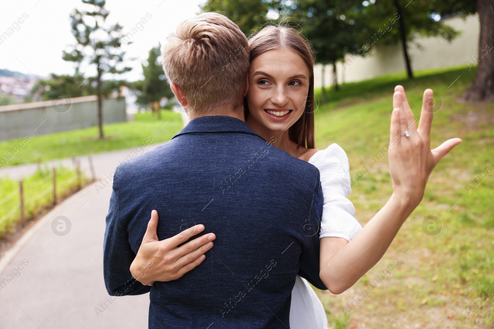 Marriage proposal. Smiling woman with engagement ring hugging her fiance outdoors Photo of Marriage proposal. Smiling woman with engagement ring hugging her fiance outdoors