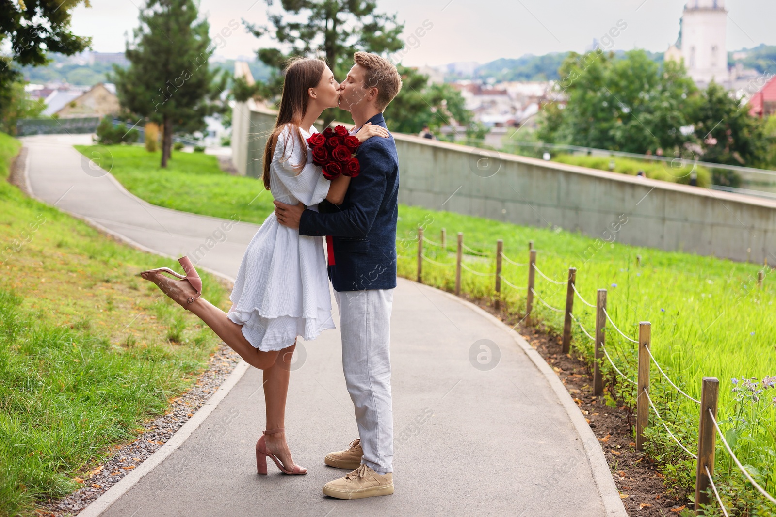 Marriage proposal. Man kissing his beloved with bouquet of roses on engagement day outdoors Photo of Marriage proposal. Man kissing his beloved with bouquet of roses on engagement day outdoors