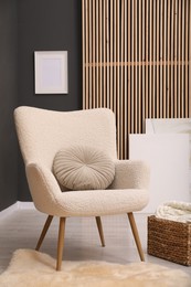 Photo of Contemporary armchair with pillow, rug and wicker basket indoors. Interior design