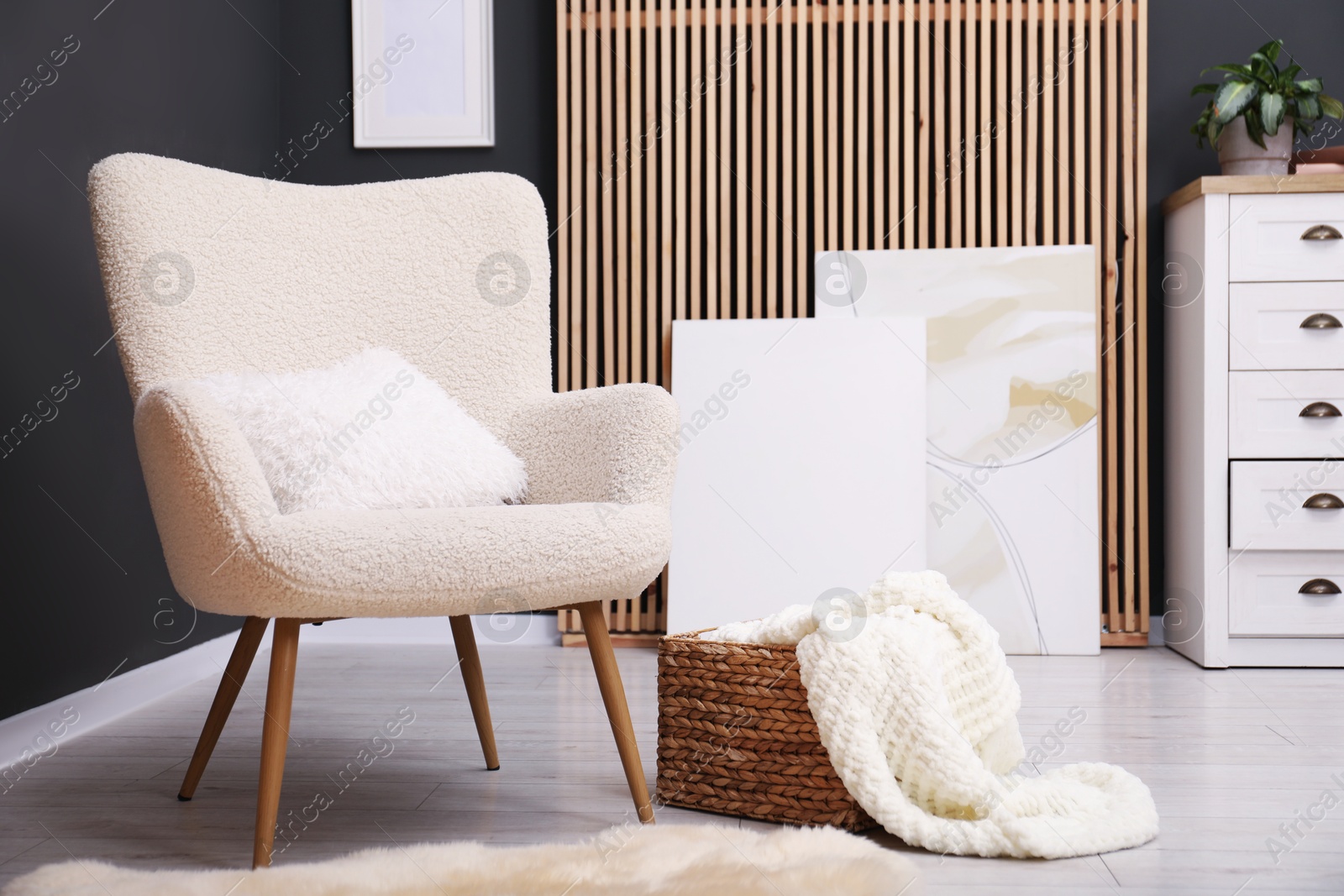 Photo of Contemporary armchair with pillow, rug and wicker basket indoors. Interior design