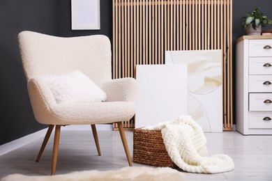 Photo of Contemporary armchair with pillow, rug and wicker basket indoors. Interior design