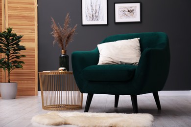 Photo of Contemporary armchair with pillow, rug and side table indoors. Interior design