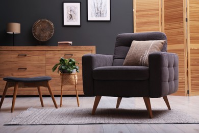 Photo of Contemporary armchair with pillow, bench and houseplant indoors. Interior design