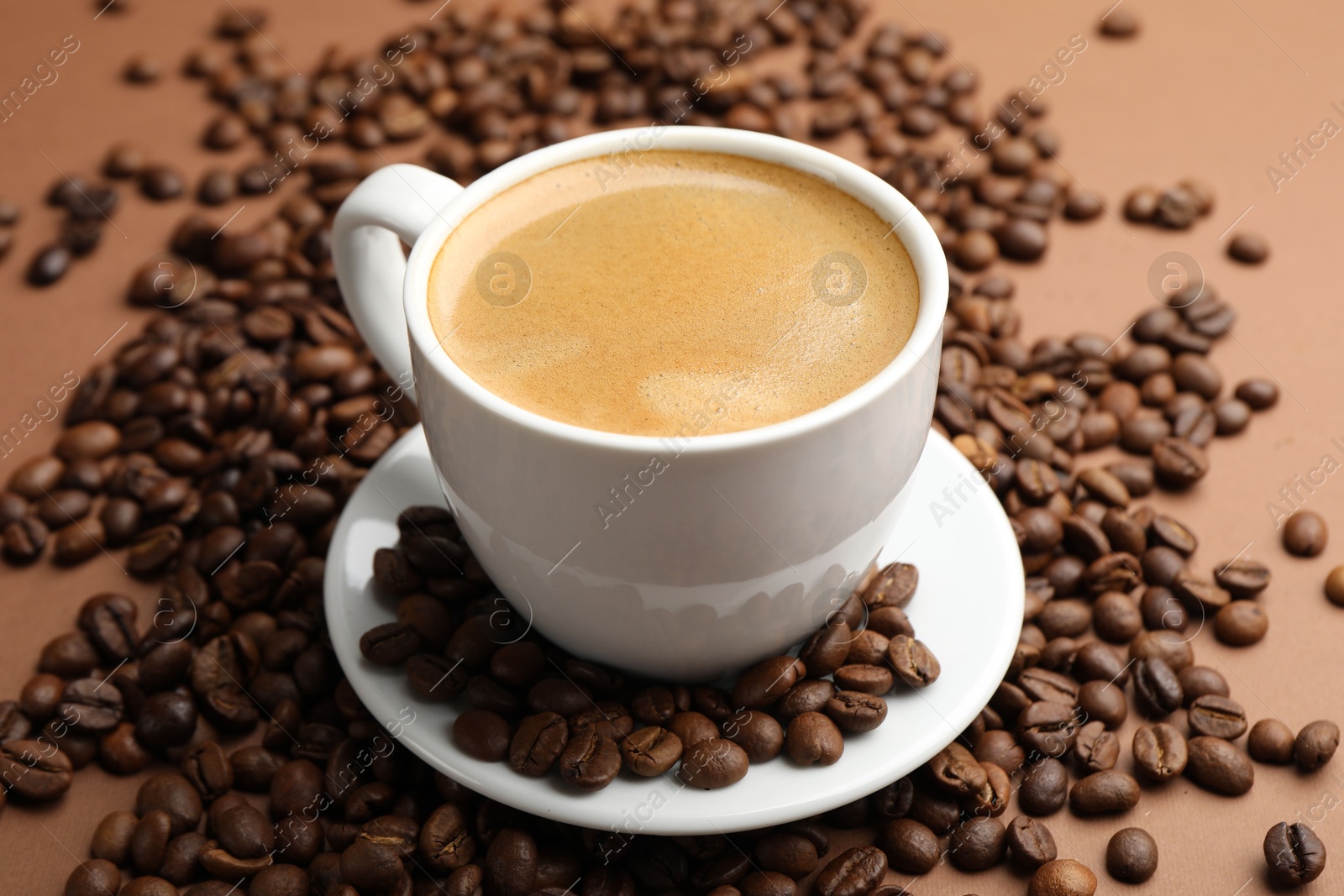 Cup of hot coffee and beans on brown background, closeup Photo of Cup of hot coffee and beans on brown background, closeup