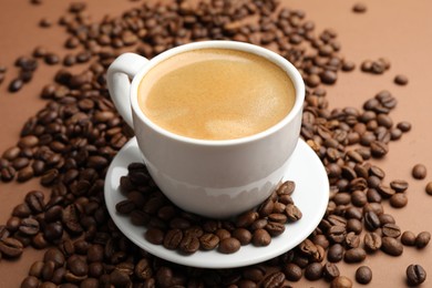 Photo of Cup of hot coffee and beans on brown background, closeup
