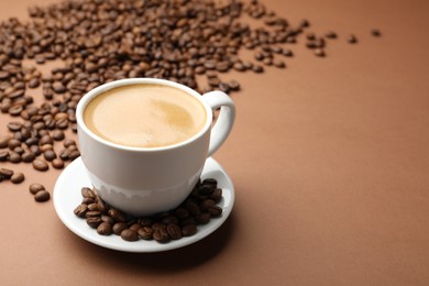 Photo of Cup of hot coffee and beans on brown background, closeup. Space for text
