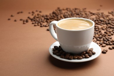 Photo of Cup of hot coffee and beans on brown background, closeup. Space for text