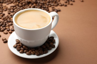 Photo of Cup of hot coffee and beans on brown background, closeup. Space for text