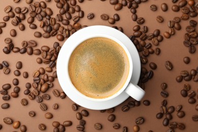 Photo of Cup of hot coffee and beans on brown background, flat lay
